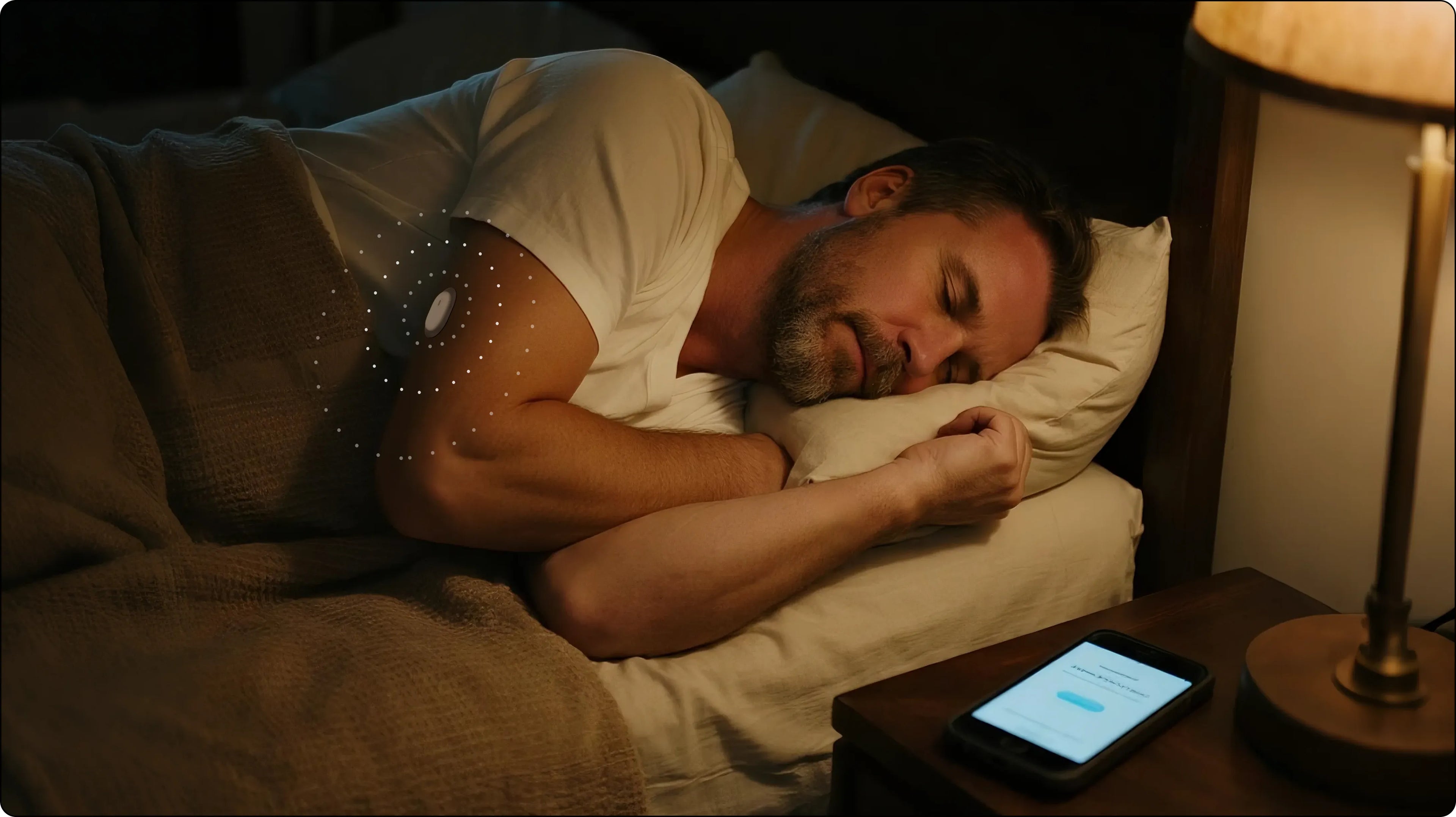 Sleeping man with a glucose monitor on his arm. Blood sugar reading 59 mg/dL. Nighttime scene with phone and lamp. Keywords: glucose monitor, blood sugar, sleep.
