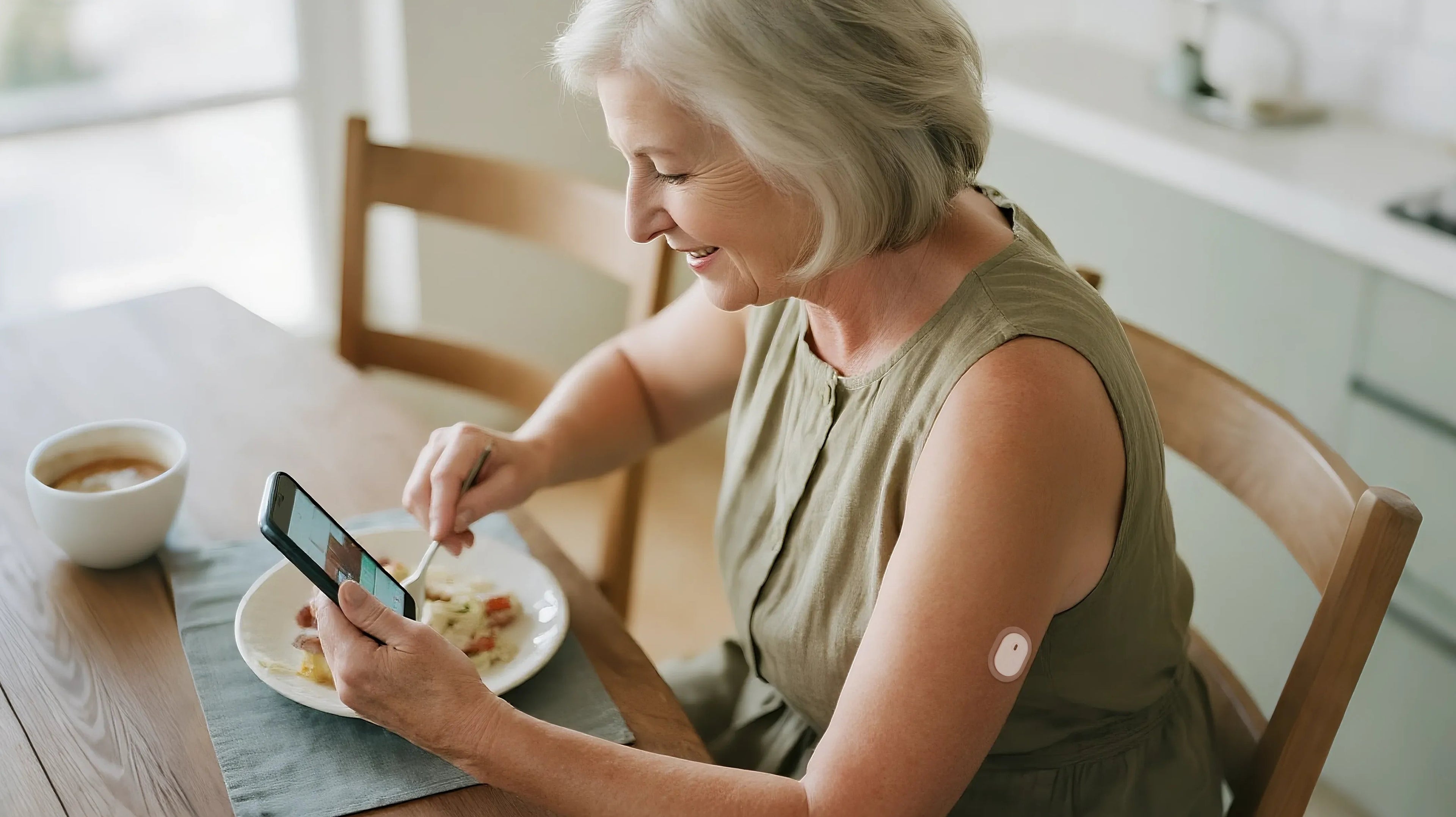 An elderly woman uses a smartphone to check her glucose level with a Sibionics monitor on her arm while eating. Keywords: glucose monitor, Sibionics, elderly, smartphone.